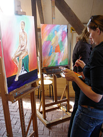 naaktmodel scjilderworkshop, een aantal deelnemers zijn druk bezig goed naar het model te kijken en dit om te zetten naar een doek met acryl verf het doek vordert al